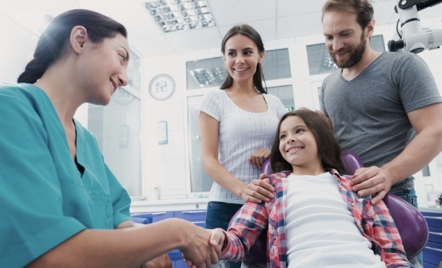 Parents and child talking to team member in dental office